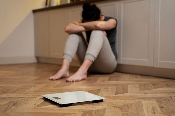 anorexia y bulimia- Joven con bulimia, sentada frenta a un peso, deprimida 