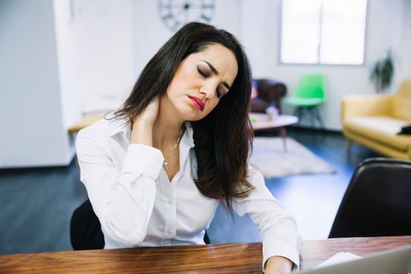 Distonía cervical - Mujer se masajea el cuello exhausta tras jornada laboral