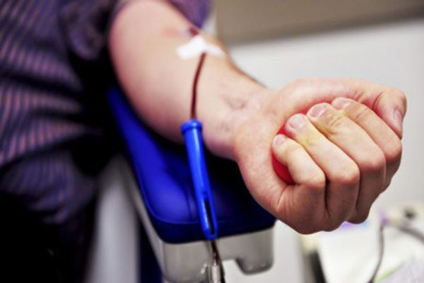 Donante de médula ósea aprieta la mano mientras le extraen sangre