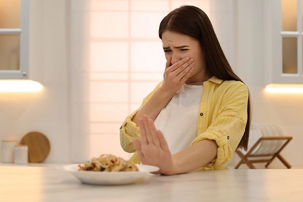 mujer joven exparimentando regurgitación de alimentos