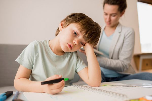 Niño disperso con TDAH tratando de realizar su tarea del colegio en casa