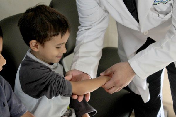 Osteogénesis - Doctor examina un pequeño paciente con fractura en el brazo