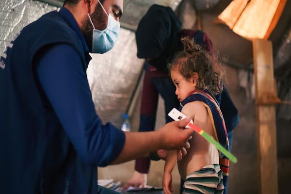 Profesional de la salud evalúa el peso y estado de salud e una niña que vive en condiciones precarias