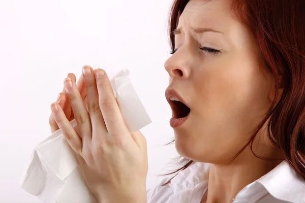 Mujer con pañuelo en mano hace un gesto facial para estornudar sin contaminar el ambiente