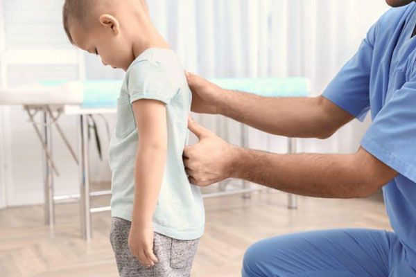 Doctor examina la curvatura de la columna de un niño de cinco años en busca de anomalías