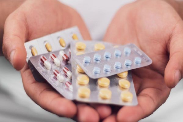 Mujer sostiene varios blísteres de antibióticos en sus manos como parte de un tratamiento que le permitirá recuperar su bienestar sexual