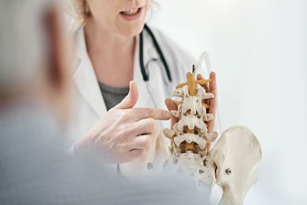 Cáncer de huesos - Doctora señala los huesos de la columna vertebral para explicar el funcionamiento y la composición de dicha estructura