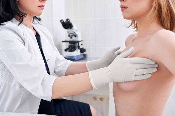 Cáncer de huesos - Doctora examina las mamas de una paciente en busca de cualquier irregularidad
