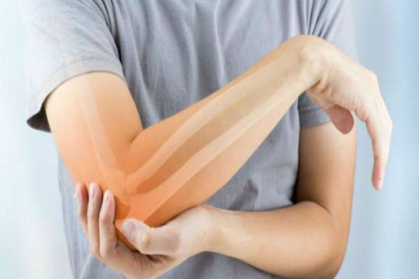 Osteomielitis - Mujer sostiene su codo tras advertir un punzante y repentino dolor