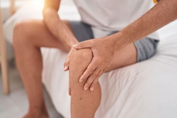Hombre sostiene su rodilla con fuerza ante persistente dolor