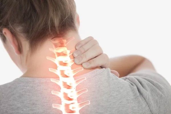 Mujer se toca la parte posterior del cuello tras experimentar un ligero dolor de columna