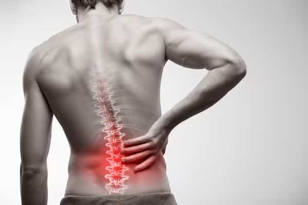 Cáncer de huesos - Hombre se lleva la mano a la parte posterior de la espalda tras persistente dolor de columna