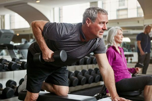 Pareja de adultos mayores acuden juntos al gimnasio para ejercitarse con pesas y diversas rutinas de cardio