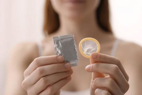 Joven rompe el envoltorio de un preservativo para prevenir enfermedades de transmisión sexual