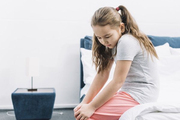 Raquitismo - Niña con dolor fuerte en la rodilla, debido a la deficiencia de vitamina D que causa la enfermedad del raquitismo