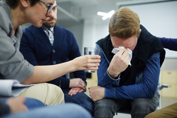 Amigos conversando y comprendiendo a un hombre que se siente deprimido por su adicción a las drogas, la cual está destruyendo su vida