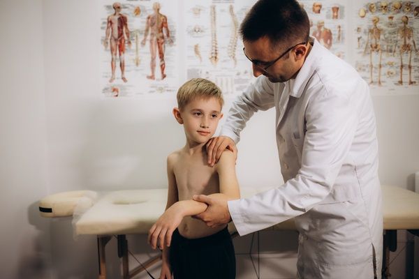 Doctor evaluando a un niño con problemas óseos en columna vertebral, para recomendar el tratamiento adecuado que permita evitar complicaciones a largo plazo