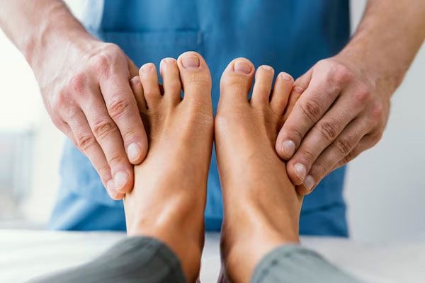 Doctor examina y masajea los huesos del pie de una paciente para acelerar su recuperación tras una lesión