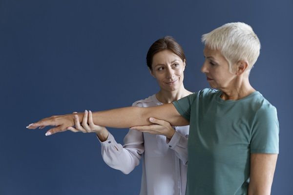 Mujer mayor realizando ejercicios con una terapeuta, para mejorar la masa muscular y evitar afecciones en las articulaciones