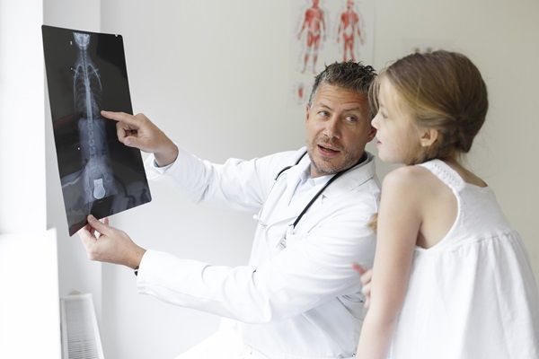 Raquitismo - Doctor evaluando la radiografía de una niña con raquitismo, para tener un diagnóstico preciso de la afección y recomendar el tratamiento adecuado