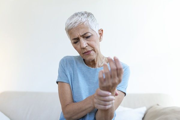 Qué es la osteoporosis - Mujer de edad avanzada sintiendo dolor en la muñeca, debido al debilitamiento óseo causado por la osteoporosis