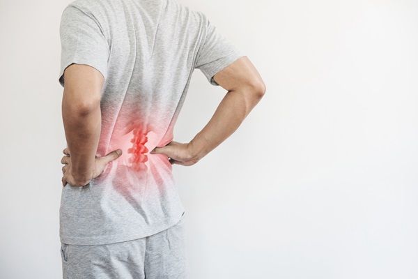 Qué es la osteoporosis - Hombre sintiendo dolor en la espalda baja, como consecuencia del debilitamiento óseo causado por la osteoporosis