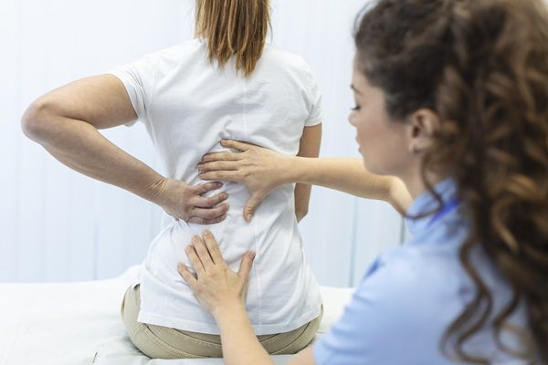 Doctora realizando un examen físico a una paciente femenina, para diagnosticar si posee una enfermedad ósea