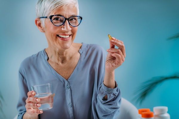 Mujer tomando un medicamento que la ayuda a fortalecer los huesos, para evitar la progresión de las enfermedades óseas