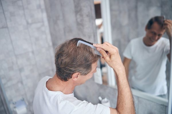 Injerto capilar Madrid - Hombre frente al espejo peinando su cabello luego de un injerto capilar precio accesible en Madrid