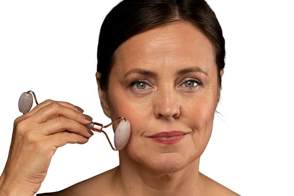 Envejecimiento prematuro - Mujer pasando un rodillo estético por el rostro para disminuir las arrugas y estimular el rejuvenecimiento facial luego de un tratamiento con bótox Madrid