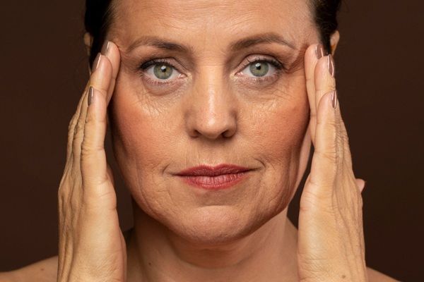 Envejecimiento prematuro - Mujer estirando las arrugas del rostro para imaginar como sería el rejuvenecimiento facial luego de conocer el precio bótox Madrid
