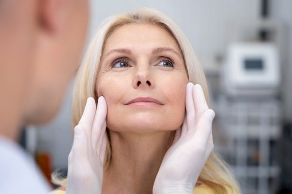 Cirujano estético evaluando el rostro de una mujer para recomendar el mejor tratamiento de rejuvenecimiento facial en una de las mejores clínicas estéticas Madrid