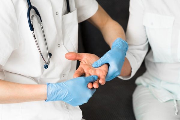 Enfermedad de Dupuytren - Médico evaluando la mano de un paciente con fibroma palmar que provoca el agarrotamiento manos debido por el bulto en la palma de la mano