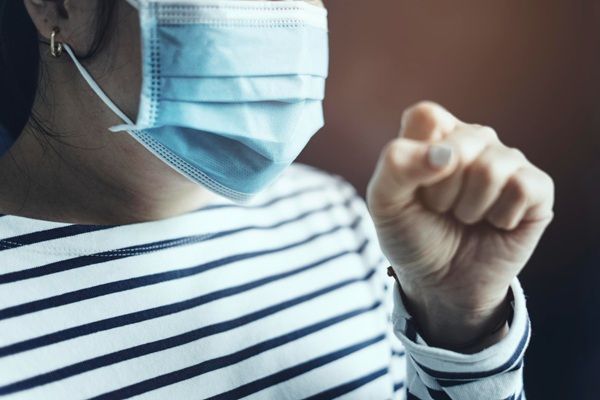 Enfermedades - Mujer usando tapabocas mientras tose debido al virus del covid 19