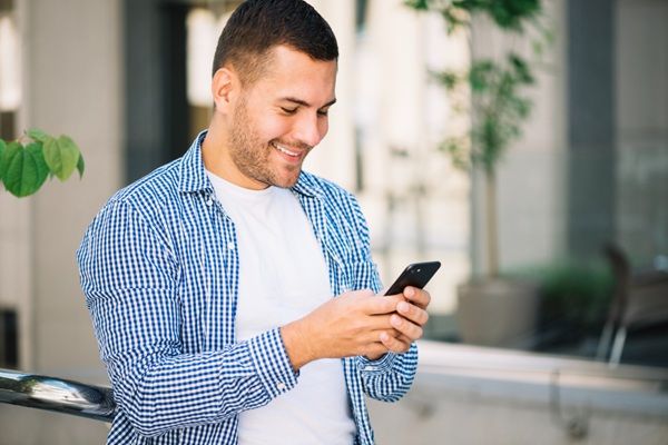 Enfermedades - Hombre usando un móvil con una postura incorrecta que puede generar enfermedades asociadas a los smartphones