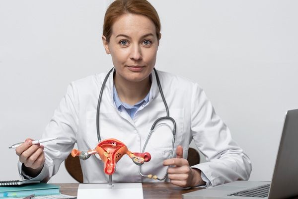 VPH - Médico especialista en infecciones de transmisión sexual señalando la maqueta del cuello uterino con virus de papiloma humano por ETS