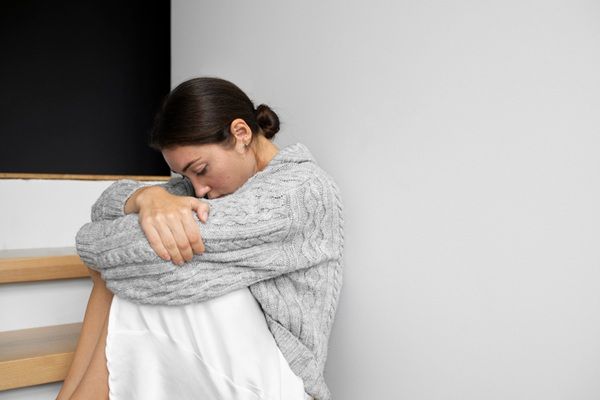 Cómo ayudar a una persona con depresión - Mujer con depresión sentada en el piso debido a crisis emocionales que afectan su estado de ánimo