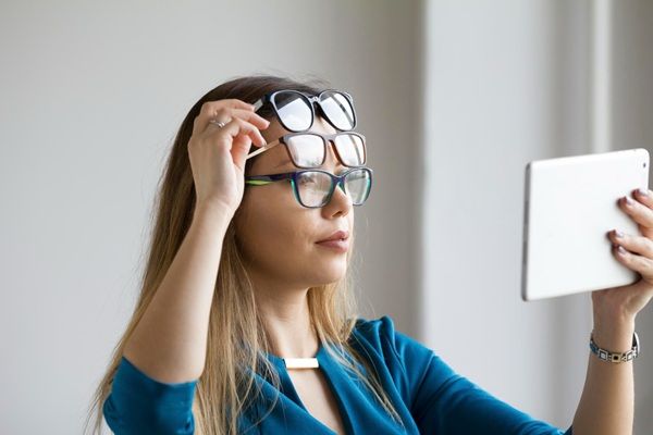 Miopía y astigmatismo - Mujer con varias gafas para evaluar el grado de afección ocular y determinar el precio operación miopía y astigmatismo