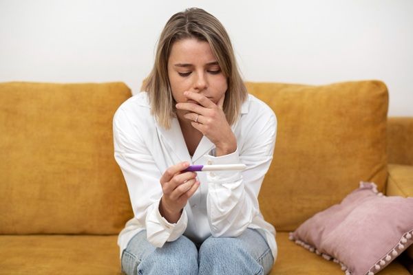Síntomas del embarazo - Mujer sosteniendo en sus manos una prueba de embarazo luego de sentir los primeros síntomas embarazo