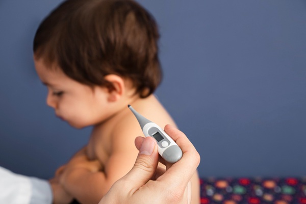 Enfermedad de Kawasaki - Especialista midiendo la temperatura de un niño con síndrome Kawasaki que provoca fiebre alta persistente