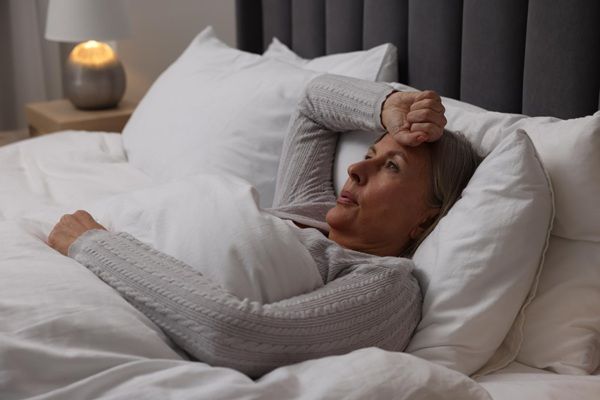 Síntomas de la menopausia - Mujer con sofocos y sudores nocturnos debido a los síntomas de la menopausia precoz
