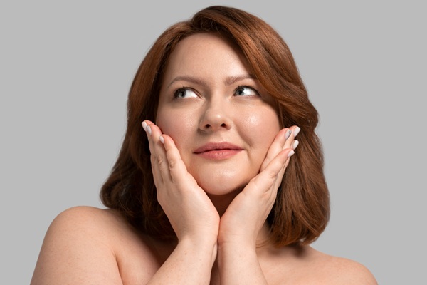 Rejuvenecimiento facial - Mujer feliz tocando su rostro radiante y sin arrugas gracias a un tratamiento facial