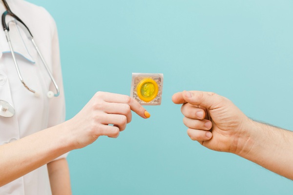 Enfermedades de transmisión sexual - Médico especialista en enfermedades venéreas dándole un preservativo a una persona para evitar ETS