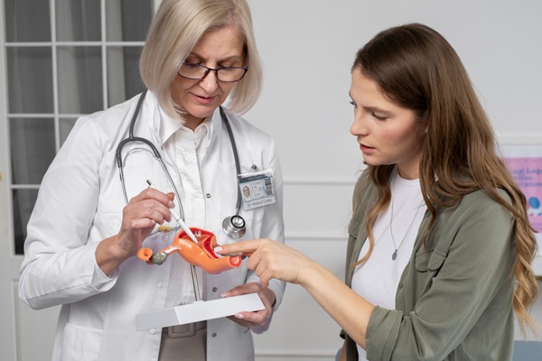 Enfermedades ginecológicas - Doctora usando una maqueta del aparato reproductor femenino para explicarle a una mujer las afecciones que presenta