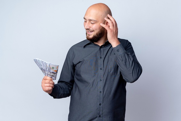 Implante capilar precio - Hombre pensativo sosteniendo el dinero para pagar el tratamiento en la mejor clínica injerto capilar Madrid