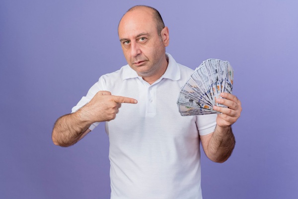 Hombre sosteniendo billetes en su mano para pagar el presupuesto de la clínica injerto capilar Madrid