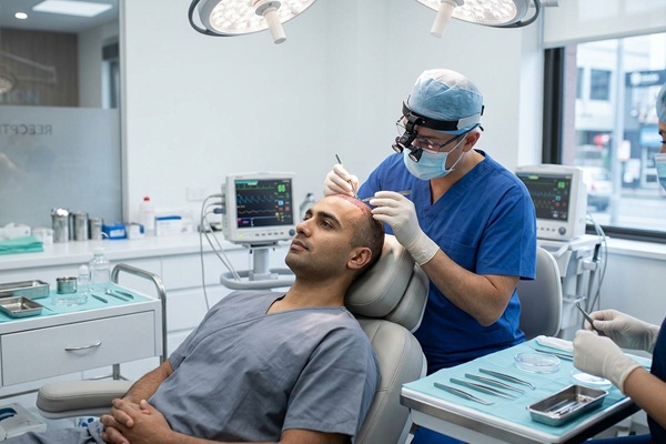 Médico tricólogo realizando un trasplante de cabello a un hombre con alopecia avanzada