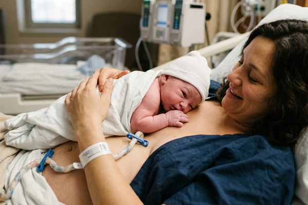 Cordón umbilical - Mujer sosteniendo al bebé luego del parto para congelar cordón umbilical