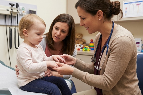 Médico especialista evaluando a una niña con anemia y deformidades óseas